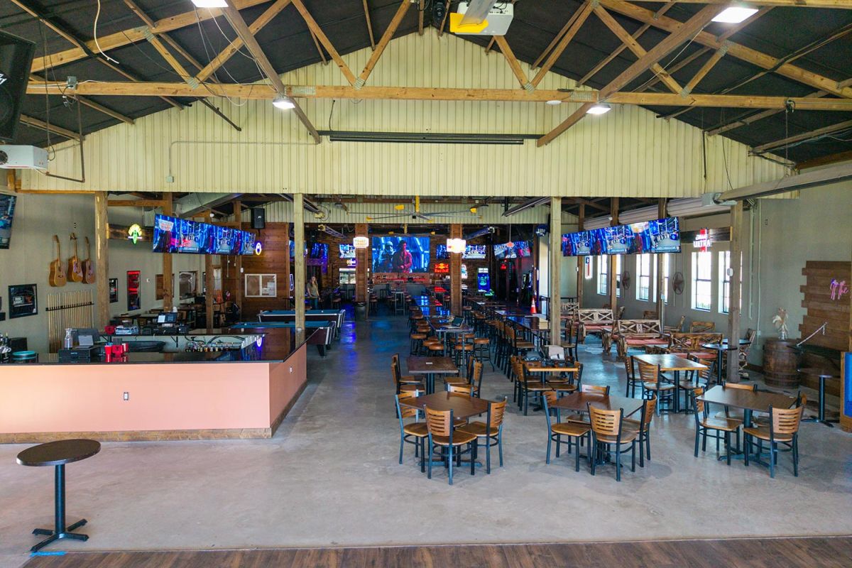 Open view of a spacious bar with wooden beams and dining tables