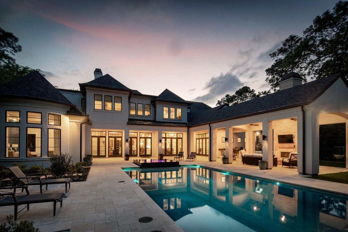 Luxury home exterior with pool and patio lit at dusk