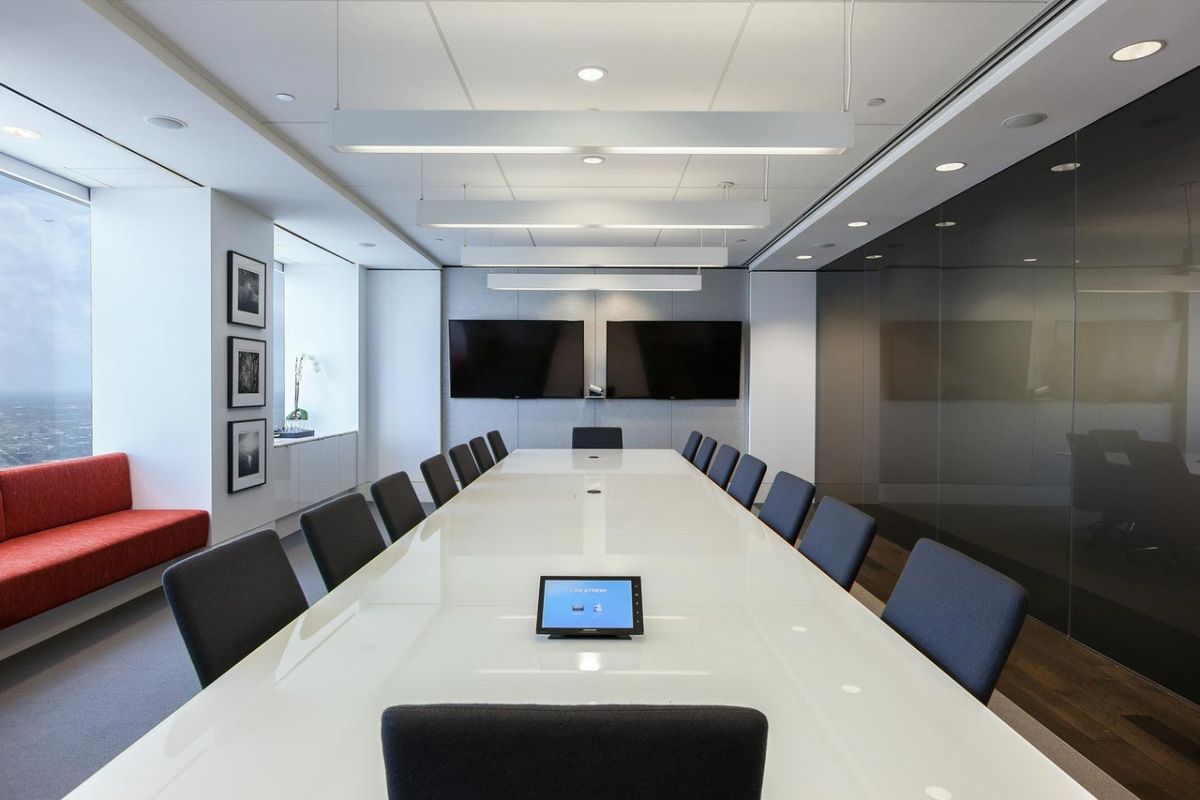 Long boardroom with large glass table and twin monitors