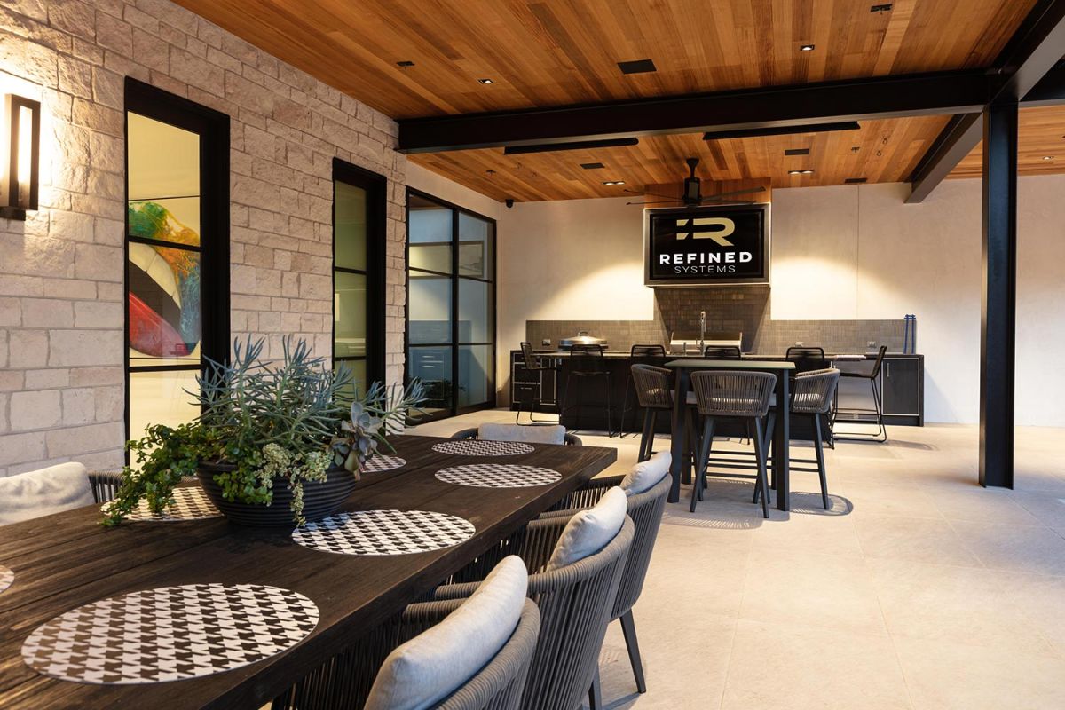 Modern outdoor kitchen and dining area with wood ceiling accents