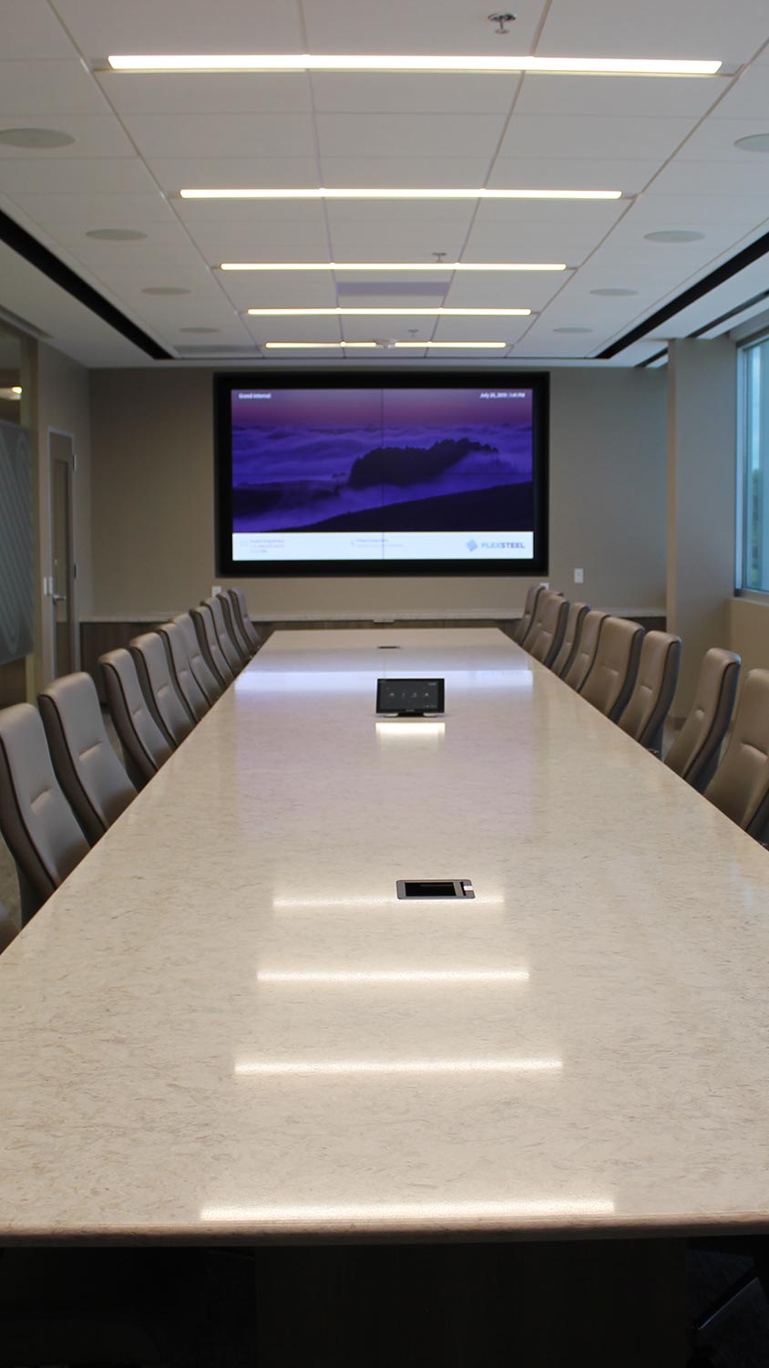 Sleek conference room with a long marble table, leather chairs, and a large screen at the front