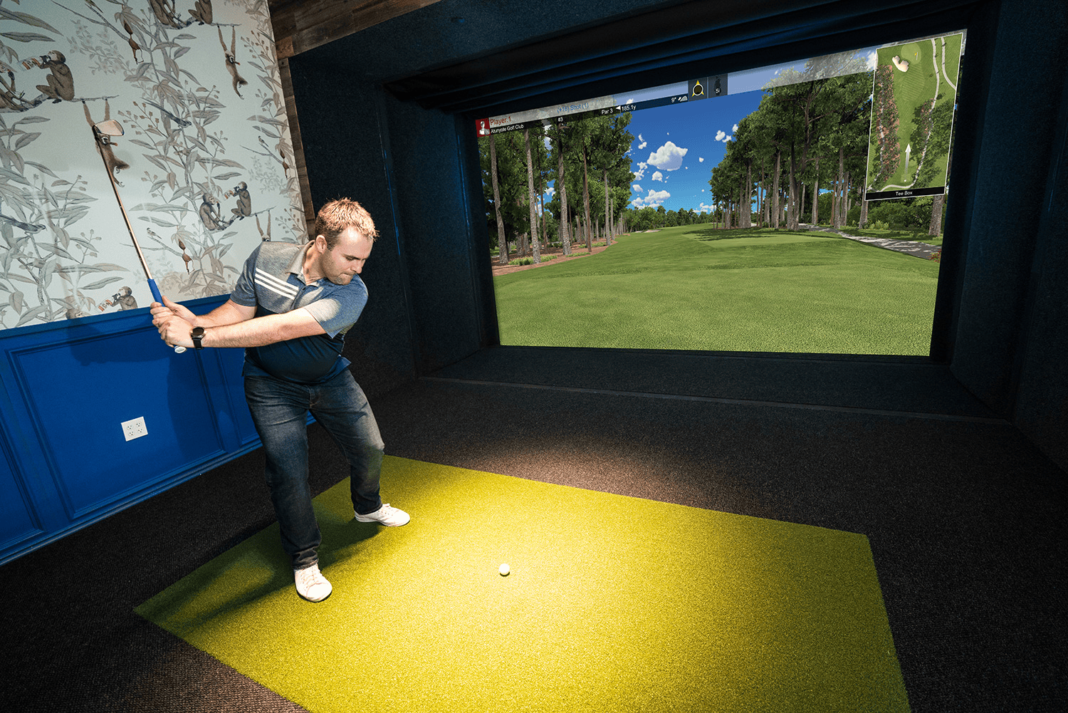 An indoor golf simulator with a projector and a realistic course display.