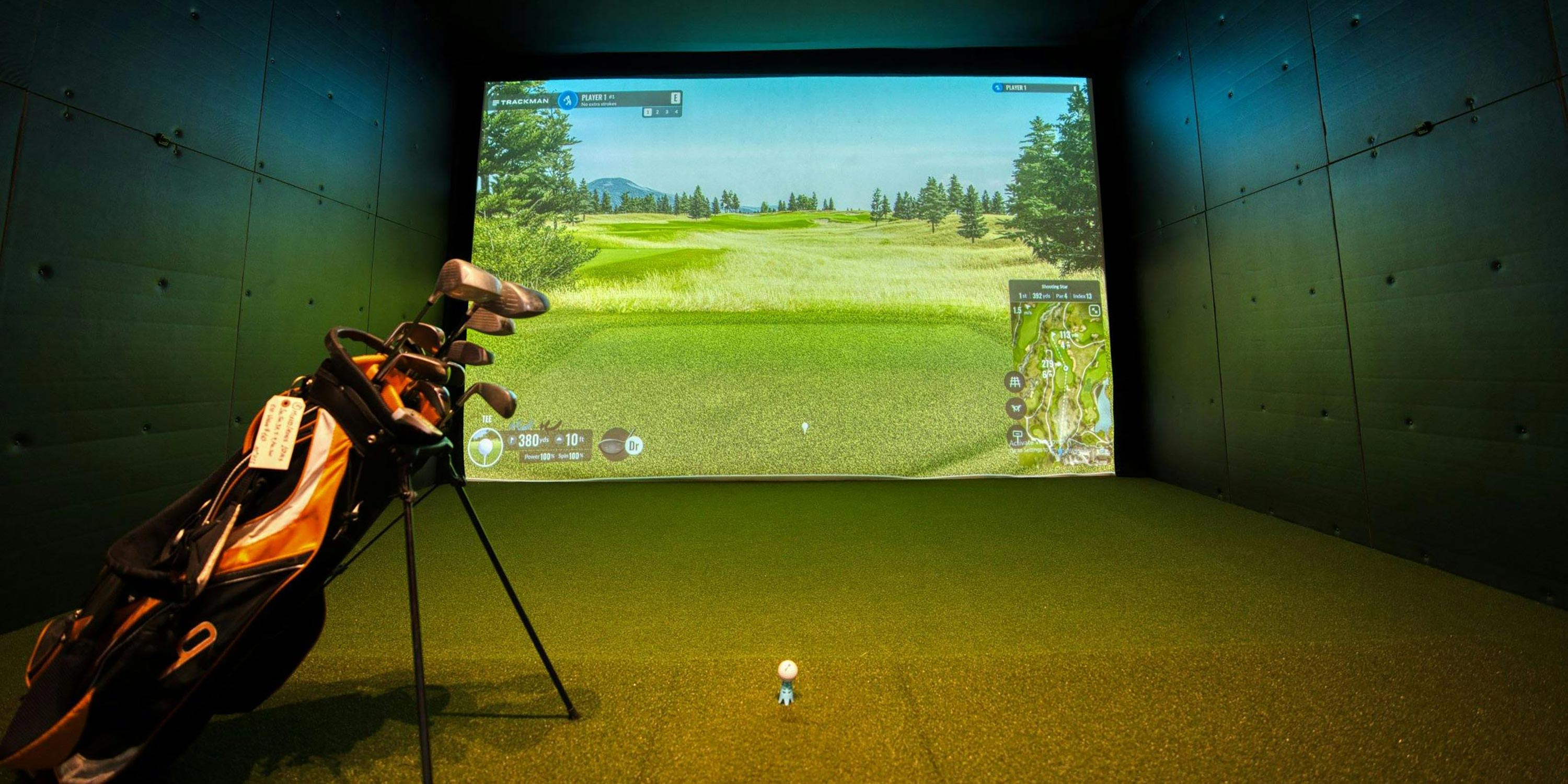 Indoor golf simulator setup with a projection screen and golf bag