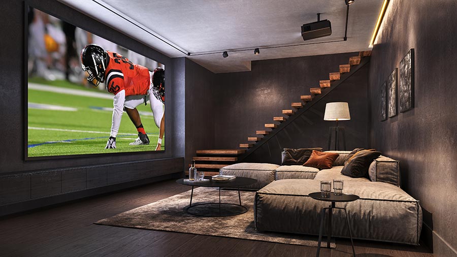 Dark modern home theater with large screen showing football game