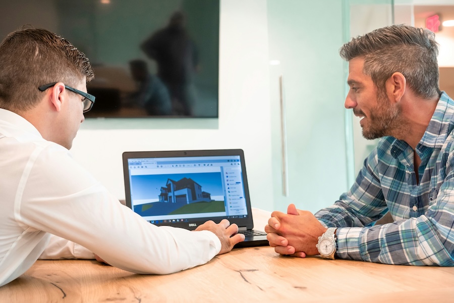 Integrator and homeowner reviewing a 3D home design on a laptop during a technology consultation.
