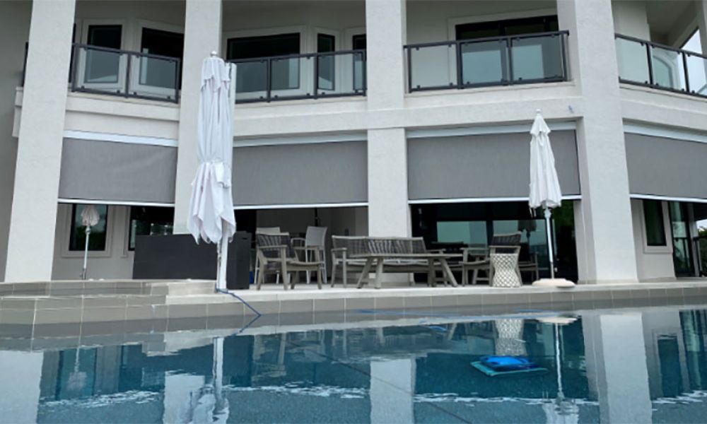 <span class="uk-h4">A luxurious outdoor patio with MagnaTrack motorized screens beside a large pool area.</span>