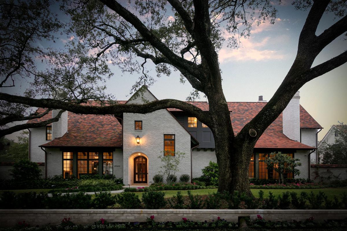 Elegant house exterior with arched front door, lit lantern, and mature trees