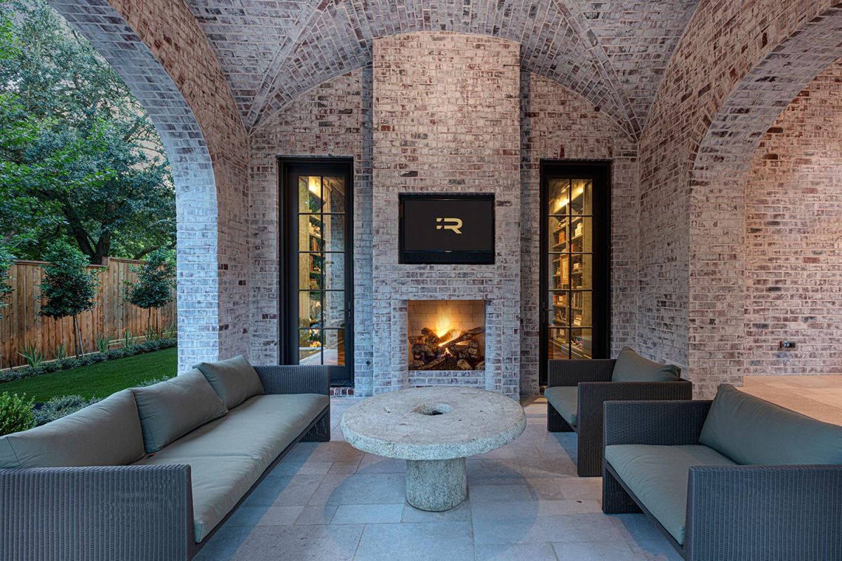 Outdoor lounge with arched brick ceiling, fireplace, and stone coffee table