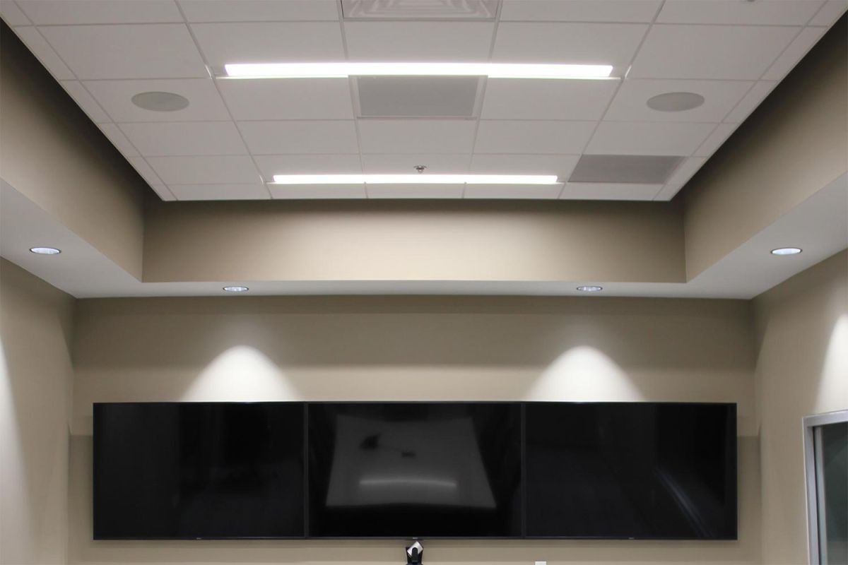 Ceiling view of recessed lighting above triple monitor setup