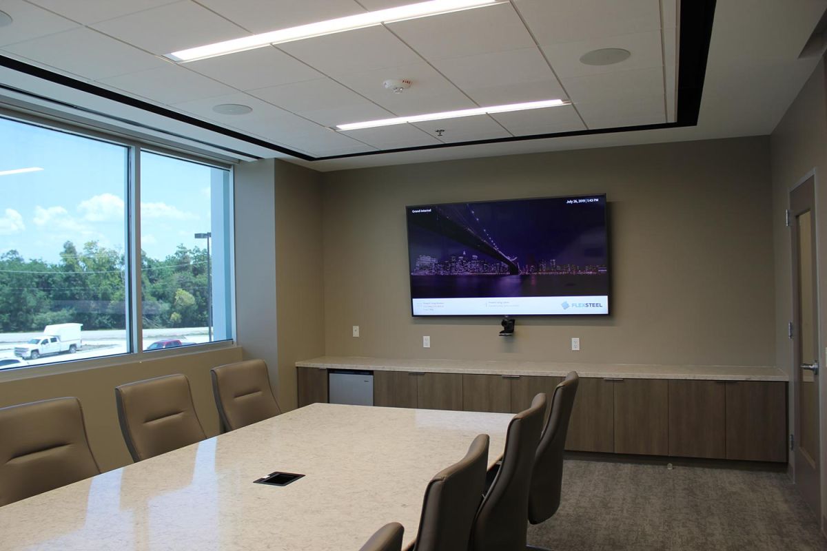 Small conference room with wall-mounted display and natural lighting