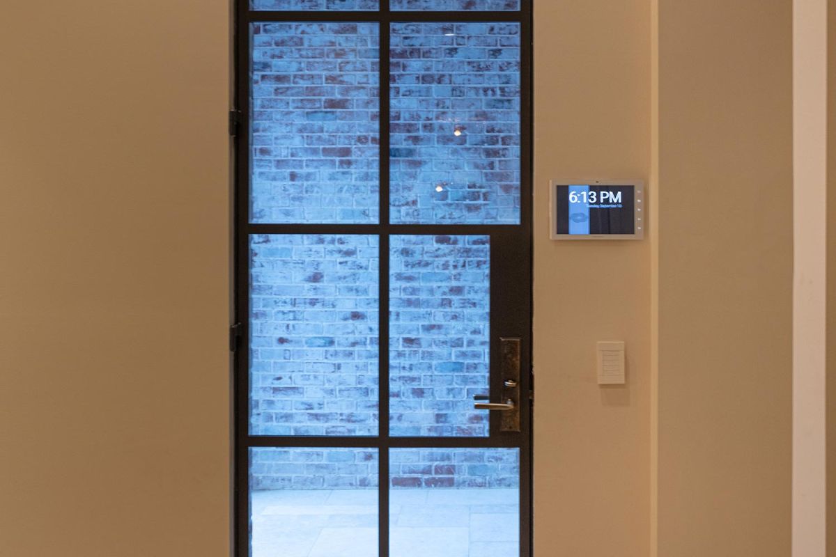 Steel-framed glass door with brick wall view and digital wall control