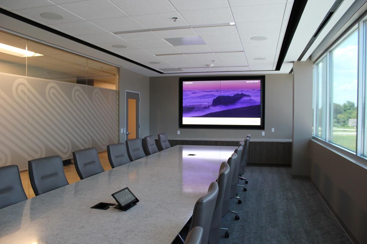 Large boardroom with long marble table and dual-screen presentation setup