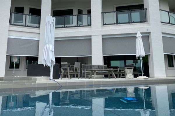 A luxurious outdoor patio with MagnaTrack motorized screens beside a large pool area.