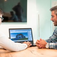 Integrator and homeowner reviewing a 3D home design on a laptop during a technology consultation.