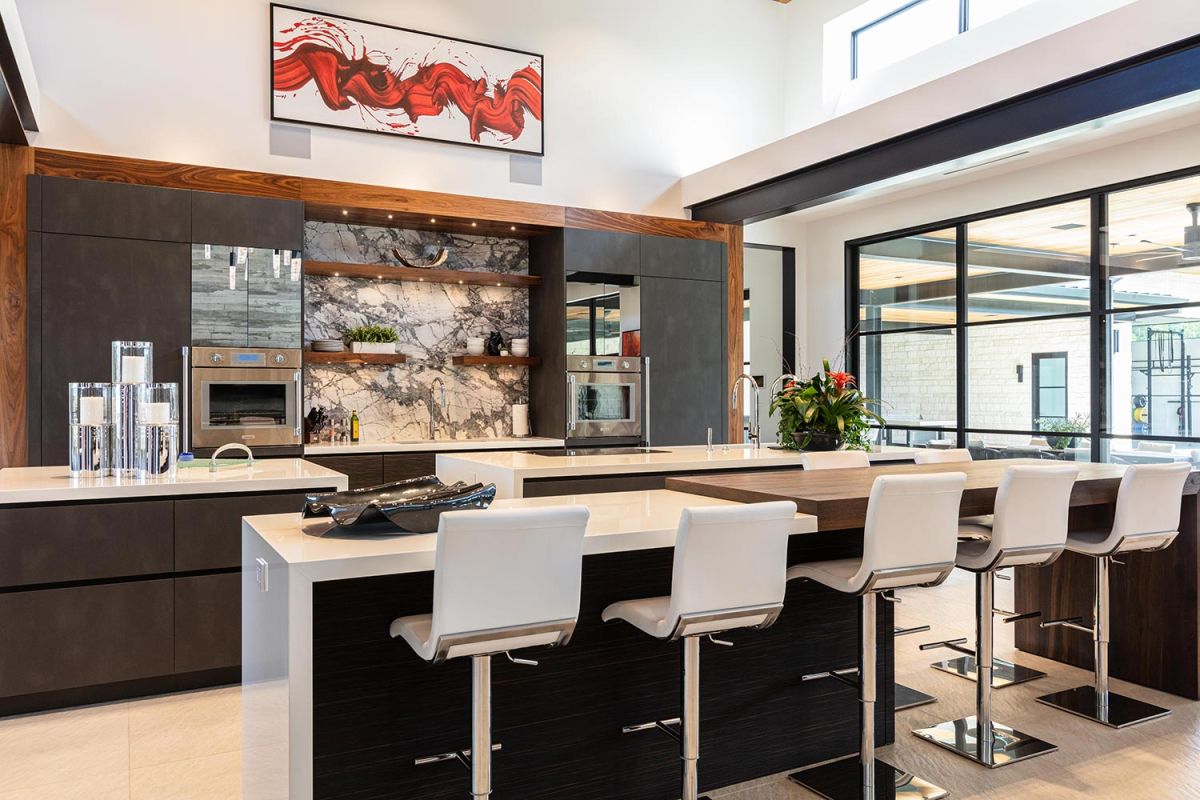 Spacious modern kitchen with marble backsplash and white stools
