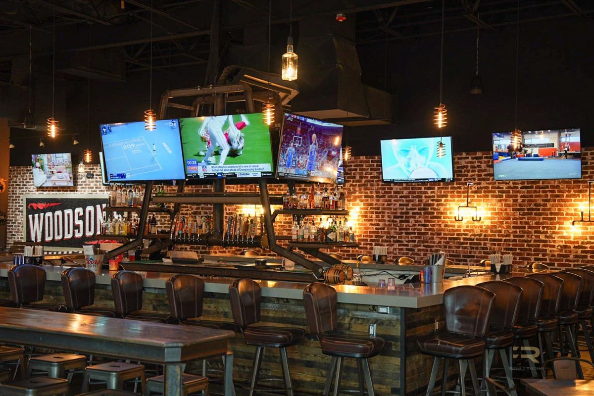 Large central bar area with TVs, bar stools, and multiple drink taps.