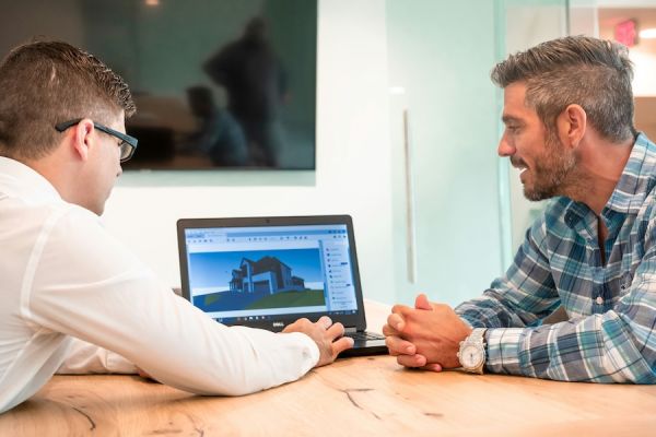 Integrator and homeowner reviewing a 3D home design on a laptop during a technology consultation.