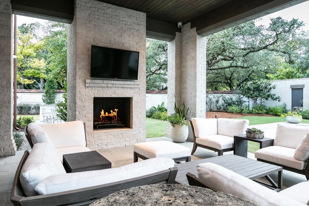 Covered outdoor seating area with fireplace, TV, and garden view