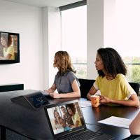 A modern conference room with automated AV technology and digital displays showcasing workplace collaboration systems.