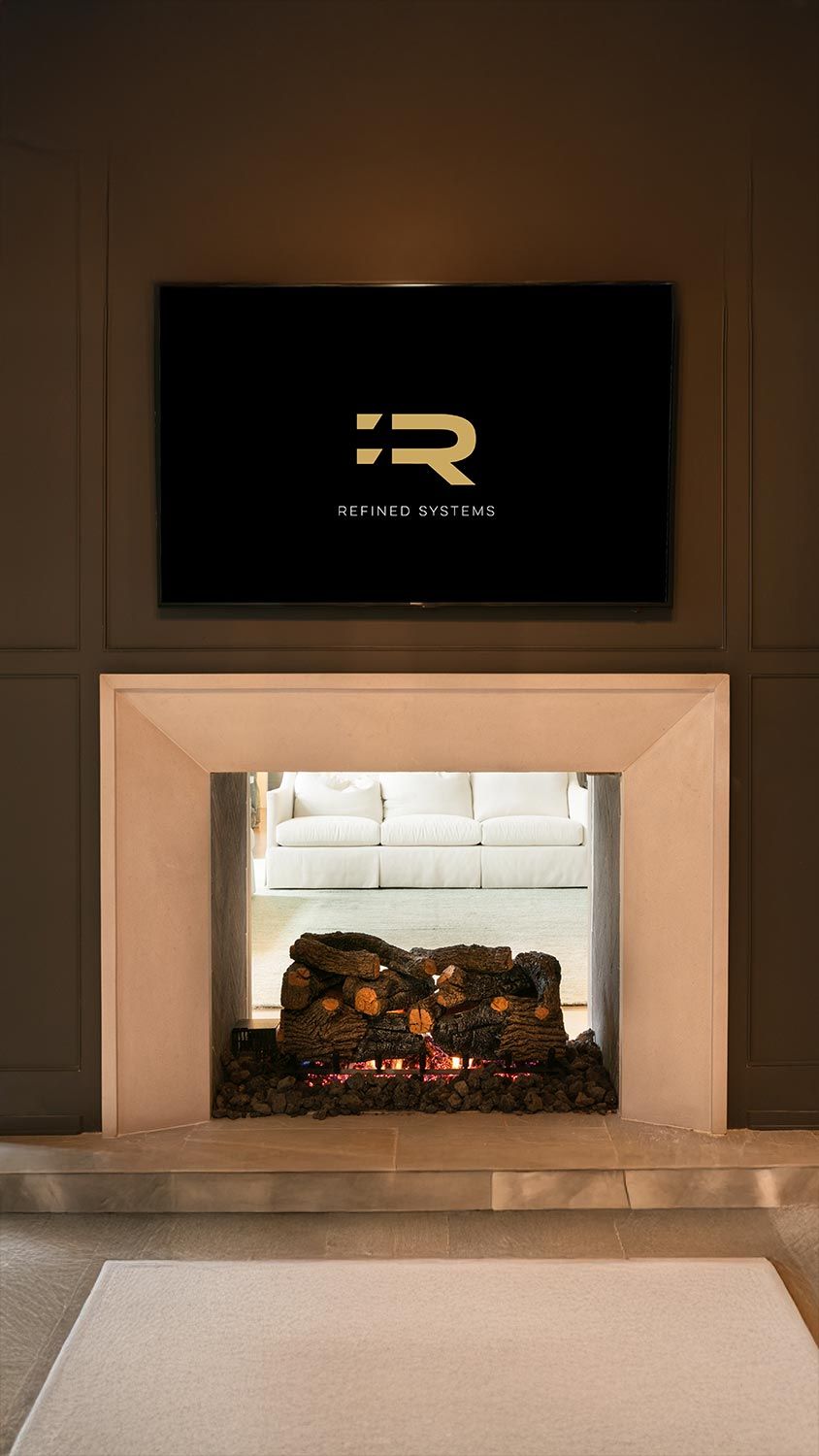 Elegant living room with fireplace, TV displaying a logo, and view into another white couch-filled room