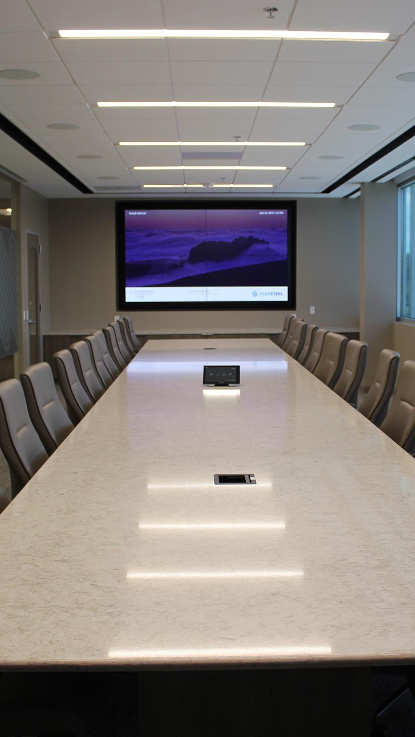 Sleek conference room with a long marble table, leather chairs, and a large screen at the front