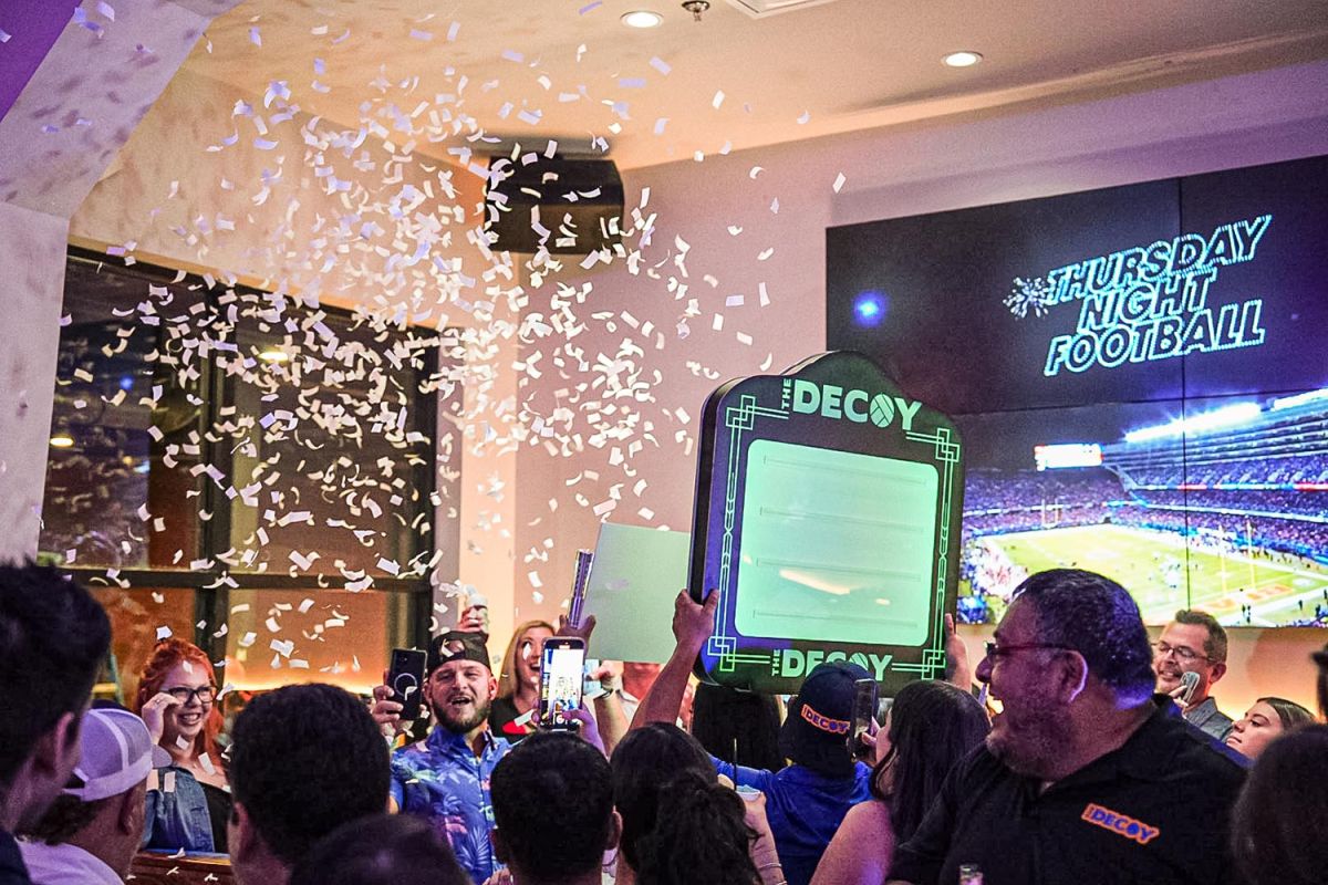 Celebration at a bar with confetti and a large screen showing a football game.